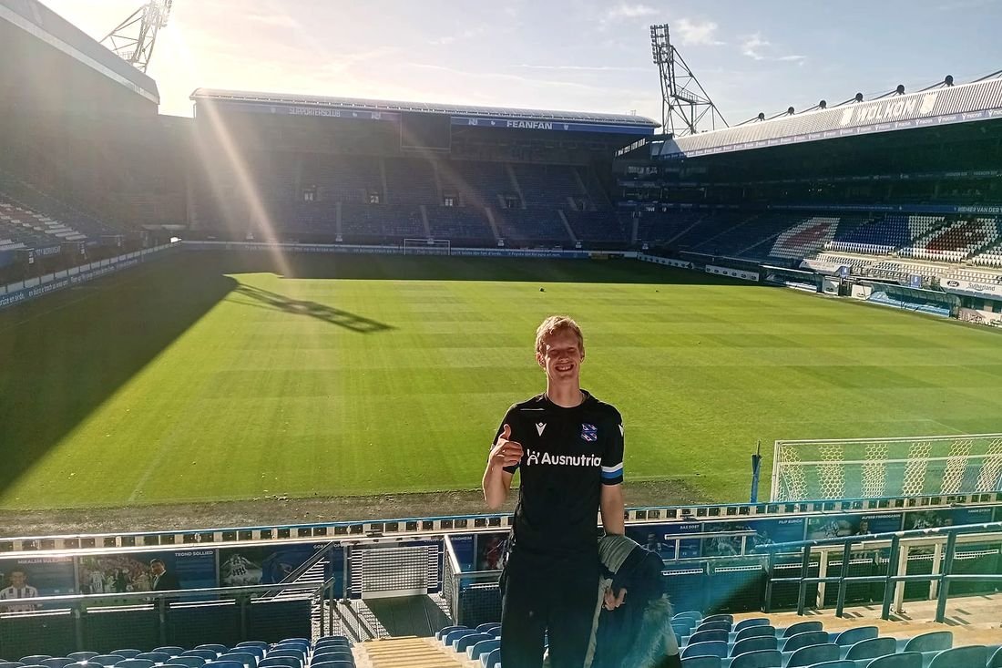 Een bewoner staat op het veld in het stadion van sc Heerenveen, met de lege tribunes om zich heen.