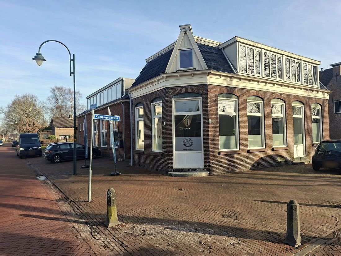Het pand van Zorggroep Maatjeshof in Rottevalle: een hoekpand van donkere baksteen met hoge ramen en het logo op de deur, op de hoek met de Kompagnonswei.
