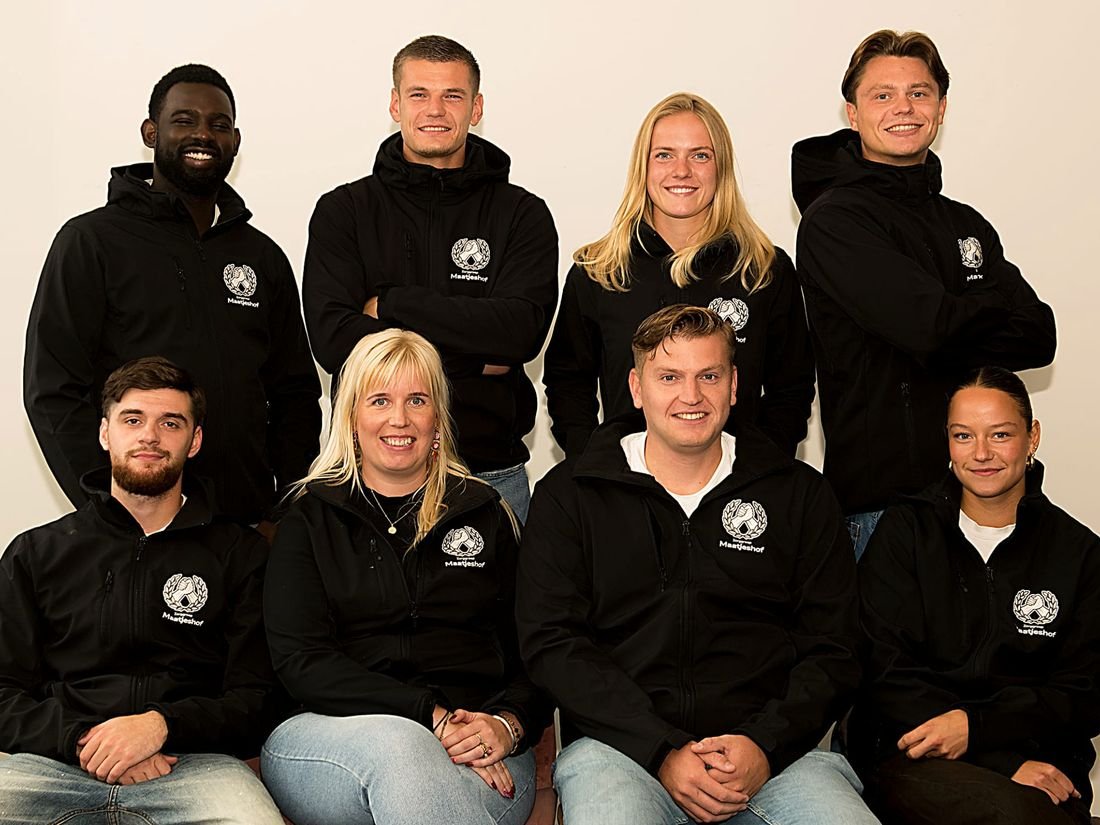 Het team van Maatjeshof in zwarte jassen met het logo: vier staan achter, vier zitten voor, allemaal lachend naar de camera.