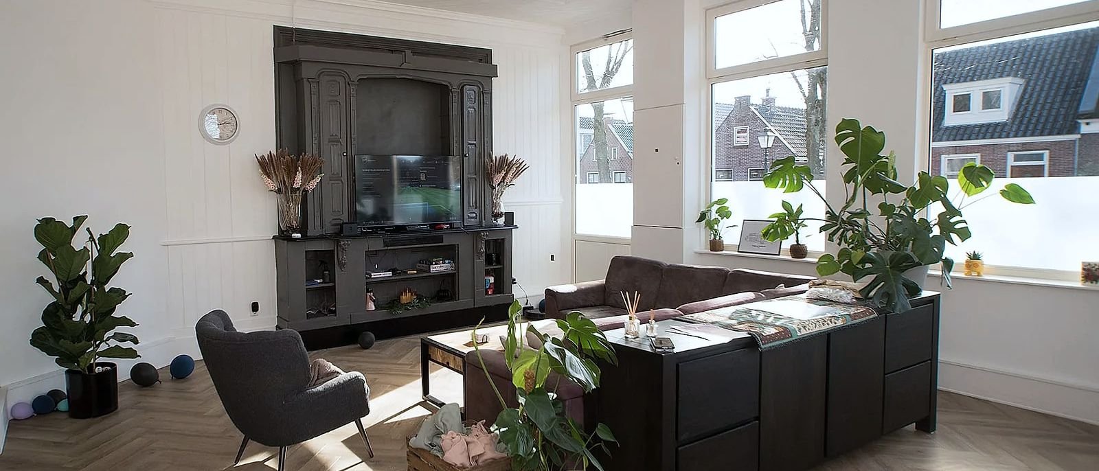 Een tweede woonkamer met een zithoek, een tv-meubel en veel planten.