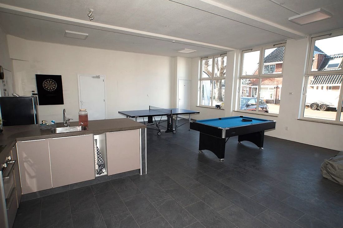 Een ruime activiteitenruimte met een pooltafel, een tafeltennistafel en een dartbord.